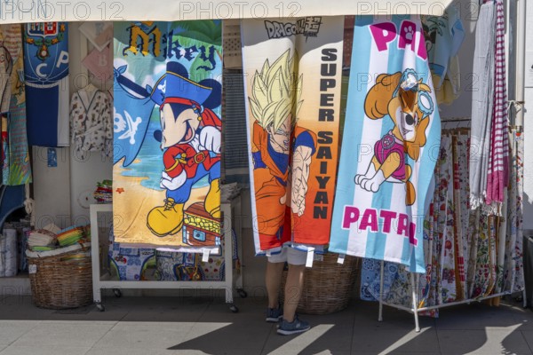 Tourists in a souvenir shop, bath towels with various comic motifs, in Vila Real de Santo António,