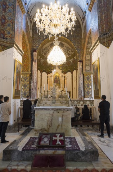 Worshippers gather in the richly decorated church with its large altar and chandeliers, Inside the