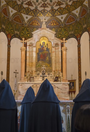 Monks pray in front of an ornately decorated altar with a religious icon, Inside the historic, most