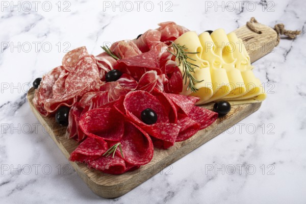 Assorted meat, appetizer, prosciutto, salami and ham, with maasdam cheese and olives, on a wooden