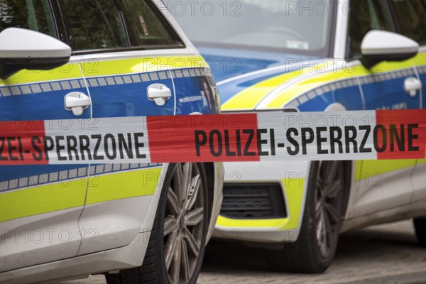 (Photomontage) Symbolic image of a police operation: police cordon in front of emergency vehicles