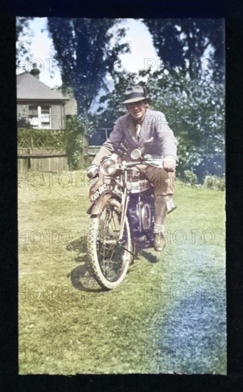 Man sitting on riding motorcycle, England, UK 1920s 1930s colourised