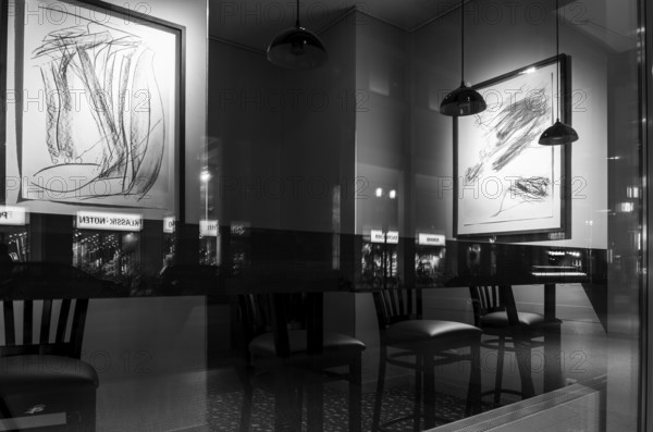 Black and white photograph, urban scene in the evening with reflections of Friedrichstraße in the
