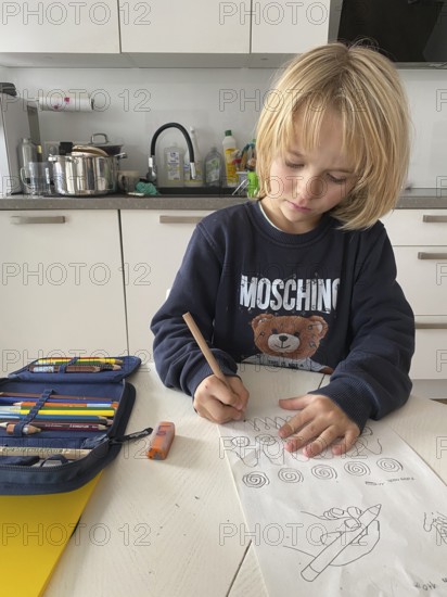 Boy, 6 years old, blond, 1st grade, practises holding the pen correctly, does homework in the