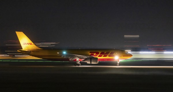 Stuttgart Airport in the early morning. DHL cargo plane landing. Light traces with motion blur.