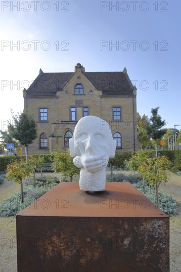 Sculpture head with headphones and hand for in front of the mouth, ambivalent symbolism for peace,
