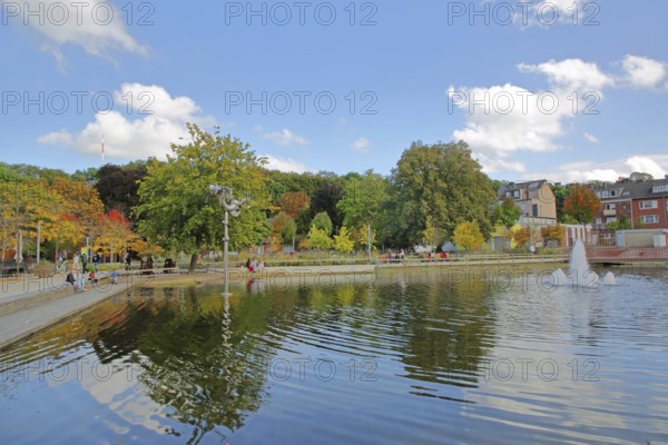 Bastinsweiher with sculpture, seating, bench, people, pedestrians, park, pond, autumn colours,