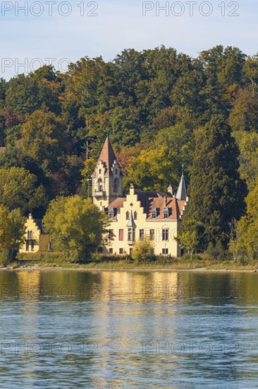 A historic manor house nestled in autumnal trees on the shore of a tranquil lake, Constance, Lake