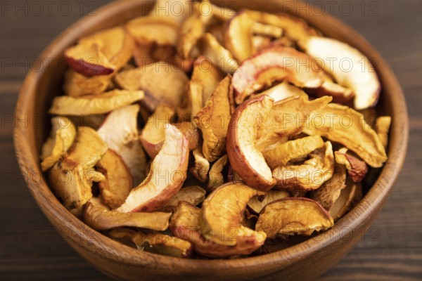 Dried Apples in wooden bowl on brown wooden background. Side view, close up, healthy food,