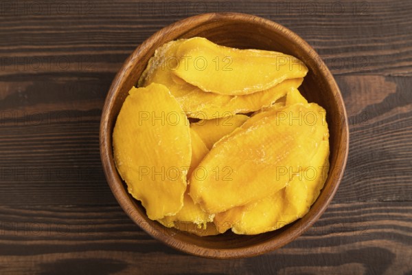 Dried Mango in wooden bowl on brown wooden background. Top view, close up, flat lay. healthy food,