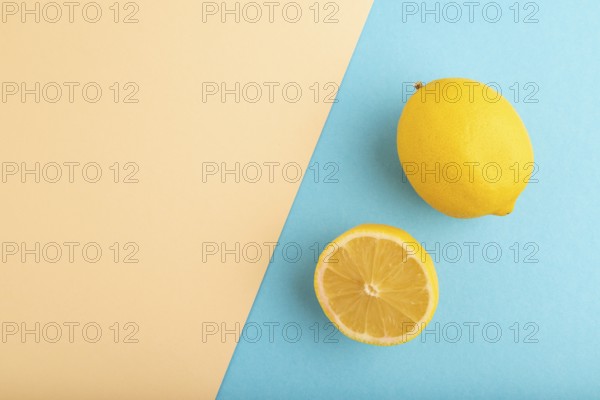 Yellow Lemon Cut in half on orange and blue pastel paper background. Top view, flat lay, copy space