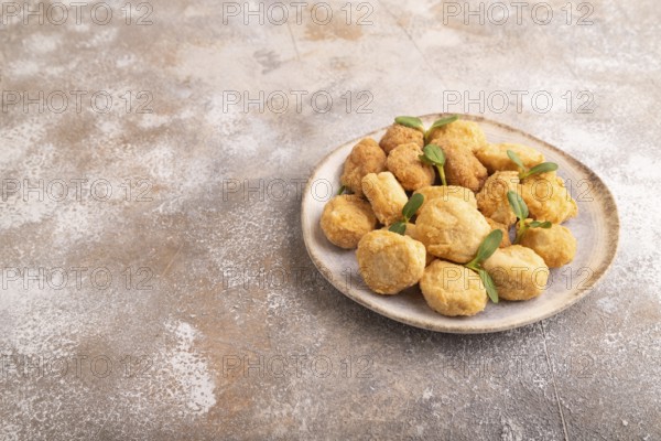 Fried crispy Chicken Nuggets with ketchup, microgreen on brown concrete background. side view, copy