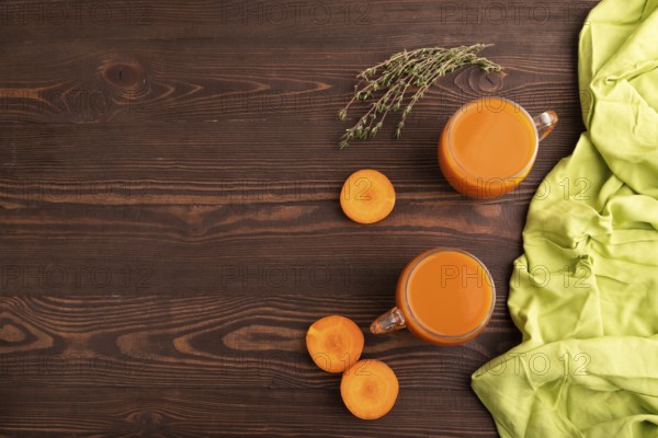 Two glasses with carrot juice, on wooden background and green textile. Diet, healthy eating concept