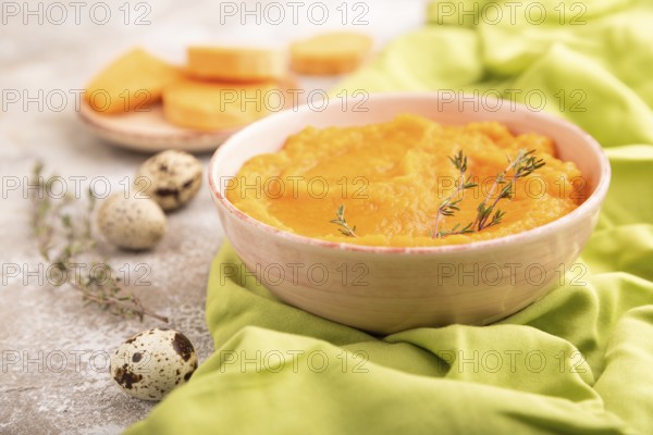 Sweet potato porridge in ceramic bowl on brown concrete background and green textile. Diet, healthy