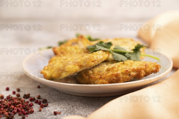 Fried crispy Chicken pancakes on brown concrete background and orange linen textile. side view,