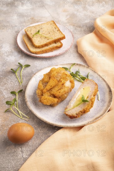 Chicken Schnitzel on blue plate with microgreen on brown concrete background and orange linen