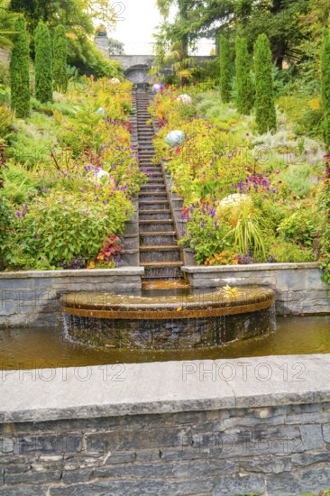 Stepped waterfall in the middle of a flowering garden with colourful plants, Mainau Island, Lake