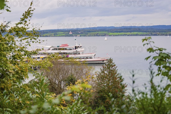 A large lake with a boat, surrounded by green landscape and cloudy sky, Mainau Island, Lake