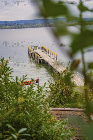 View of a jetty jutting into a calm lake surrounded by lush greenery, Mainau Island, Lake