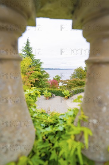 View through stone pillars of a landscape with trees and a large body of water, Mainau Island, Lake