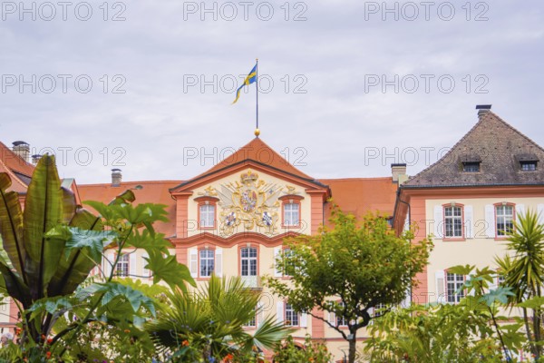 Historic building with a flag and plants in the garden, Mainau flower island, Lake Constance,