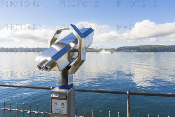 Metallic binoculars pointing to the lake with a peaceful view of the shore, Überlingen, Lake