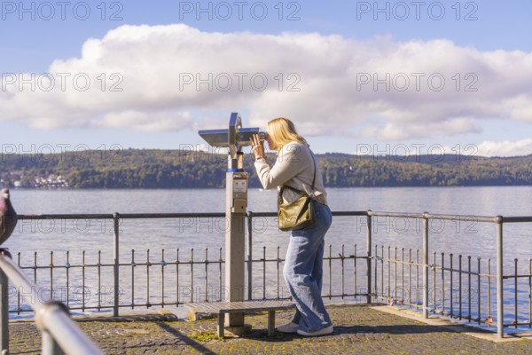 Woman using binoculars to look out over the lake from a platform, Überlingen, Lake Constance,