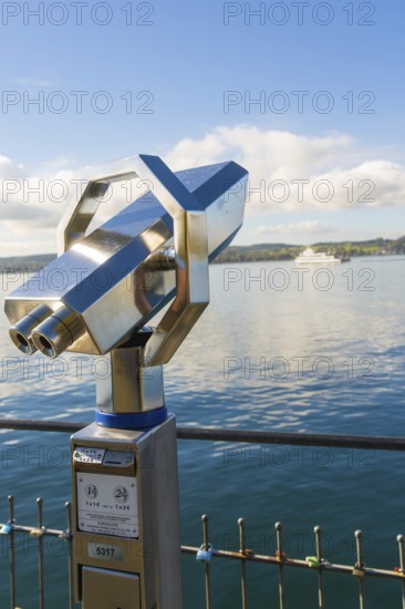 Binoculars on the shore with a ship in the background on the calm lake, Überlingen, Lake Constance,