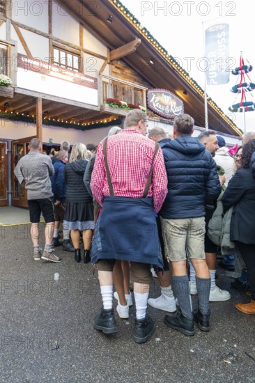 Group of people in traditional Bavarian traditional costume in front of a venue, Cannstatter Wasen