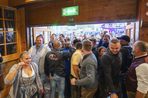 Crowd of people pushing through the entrance of a marquee, lively scene, Cannstatter Wasen folk