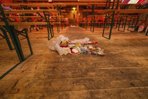 Abandoned interior with wooden benches and rubbish lying on the floor, Cannstatter Wasen folk