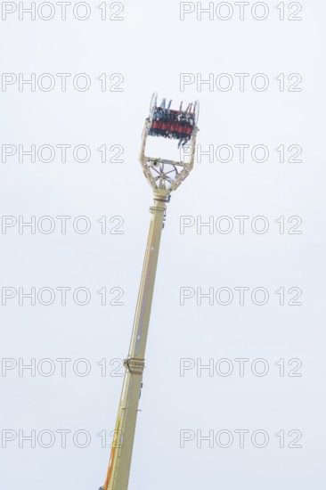 A high ride with people high in the air in front of a blue sky, Cannstatter Wasen folk festival,