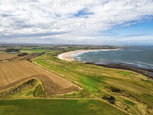 Fields and Farms over Dunstanburgh Castle from a drone, Northumberland Coast, England, United