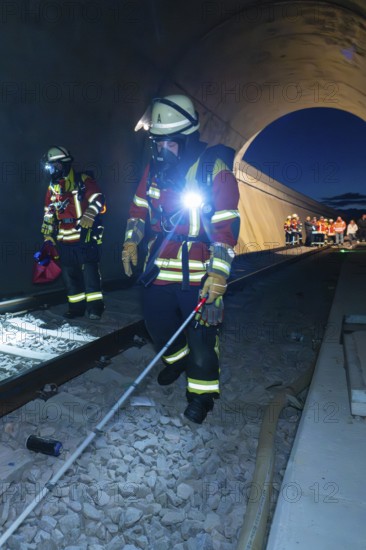 Firefighters with equipment walk along tracks in a tunnel, firefighting exercise in the new tunnel