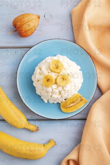 White ?ottage cheese, Curd, with Banana on blue wooden background and orange textile, top view,