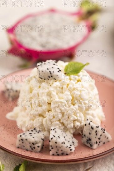 White ?ottage cheese, Curd, with Pithaya on gray concrete background and linen textile, side view,