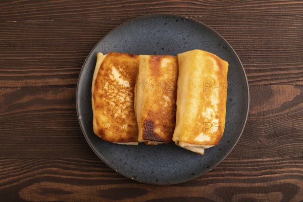 Fried crispy pancakes with meat and cheese on brown wooden background. top view, flat lay, copy