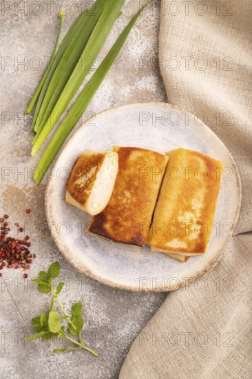 Fried crispy pancakes with meat and cheese on brown concrete background and linen textile. top