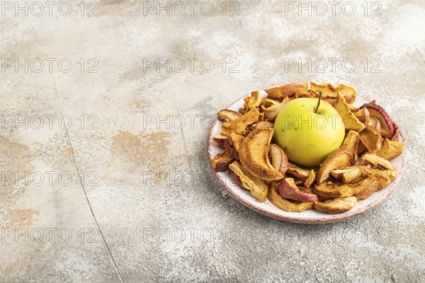 Dried Apples in ceramic bowl on brown concrete background. Side view, copy space, flat lay. healthy