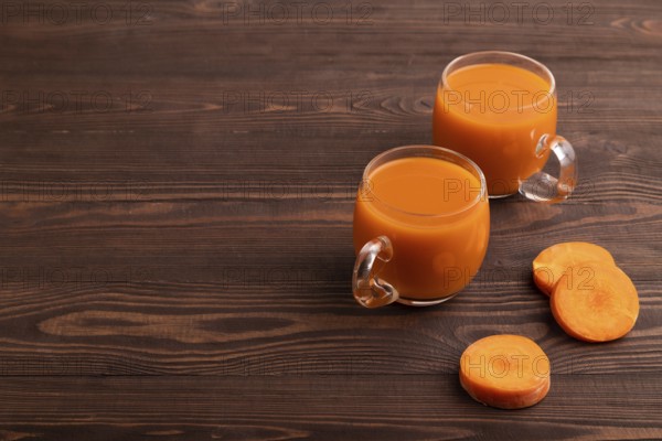 Two glasses with carrot juice, on wooden background. Diet, healthy eating concept. side view, copy