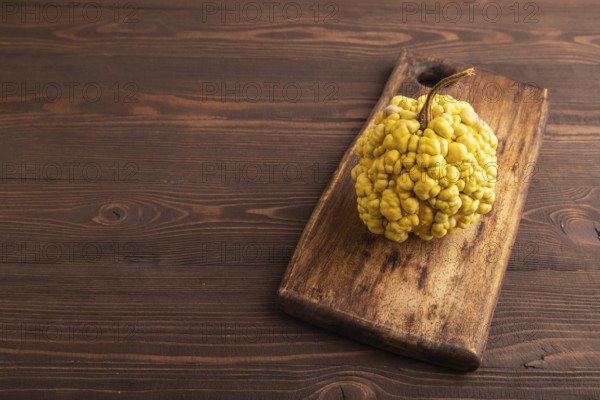 Decorative orange Pumpkin with tumors on cutting board on brown wooden background, side view, copy