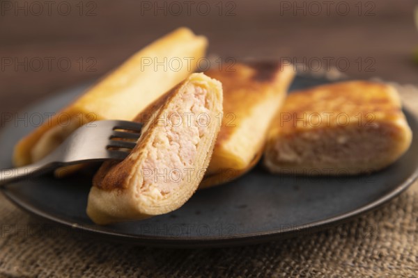 Fried crispy pancakes with meat and cheese on brown wooden background and linen textile. side view,