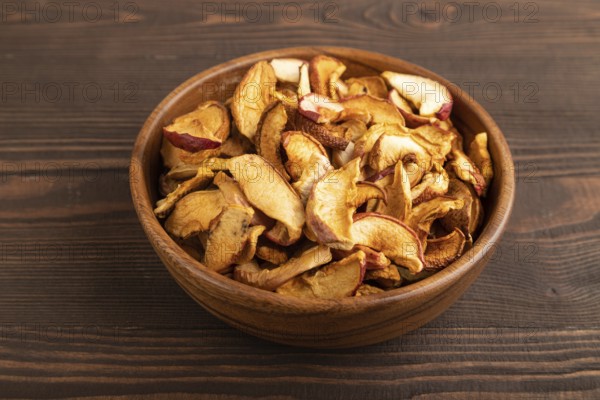 Dried Apples in wooden bowl on brown wooden background. Side view, close up, healthy food,