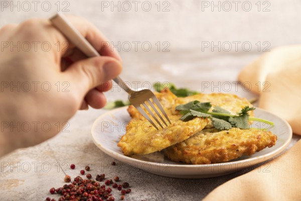 Fried crispy Chicken pancakes on brown concrete background and orange linen textile with hand. side