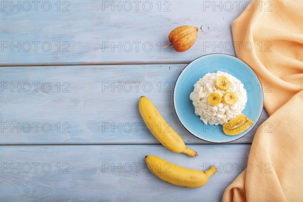 White ?ottage cheese, Curd, with Banana on blue wooden background and orange textile, top view,