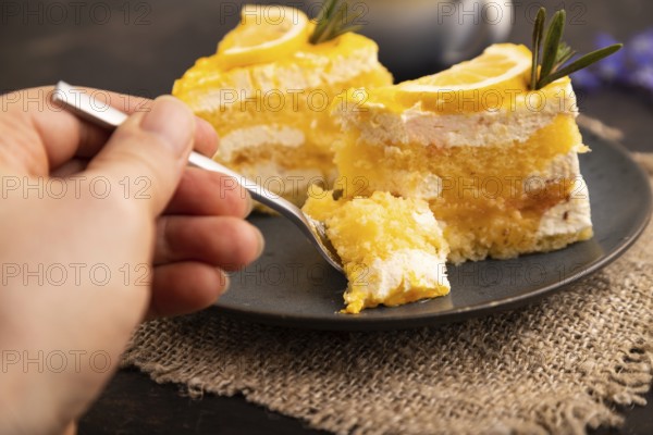 Lemon cake with hand on black concrete background and linen textile, cup of coffee, side view,