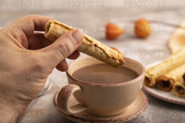 Waffles with caramel with hand on brown concrete background and orange linen textile, side view,