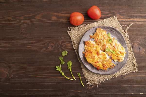 Baked chicken meat with cheese and tomatoes on brown wooden background and linen textile. top view,