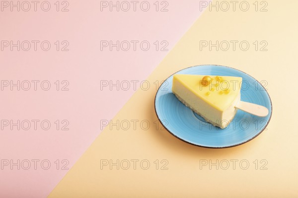 Yellow Cake pop with sprinkles on blue ceramic plate on pink and orange pastel paper background,