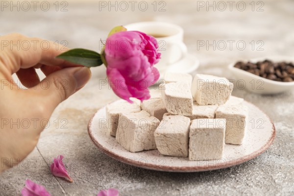 Coffee marshmallow with cup of coffee with hand on brown concrete background. side view, close up,